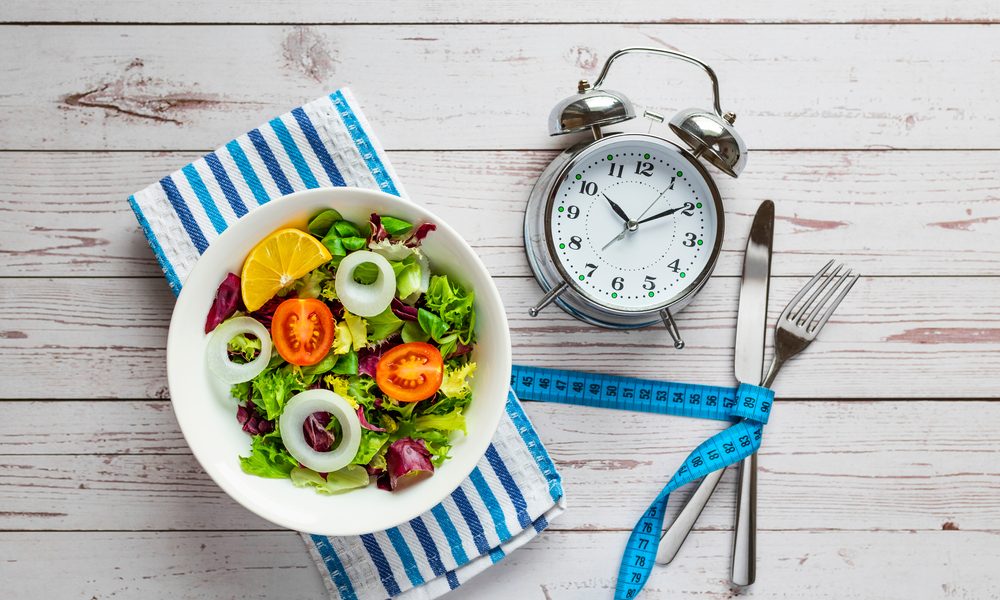 Salada e relógio em cima de uma mesa de madeira
